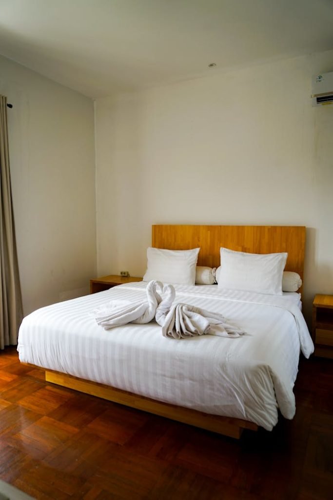 Bright and tidy hotel room featuring a double bed adorned with creative towel art.