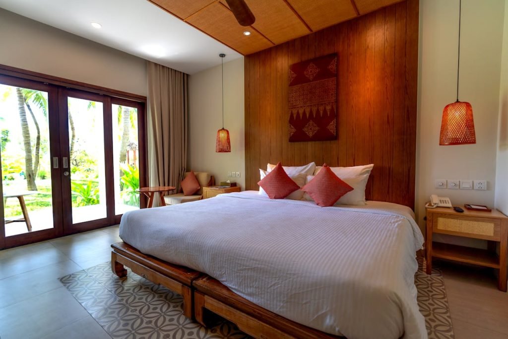Contemporary hotel room with wooden accents and large windows offering a garden view.